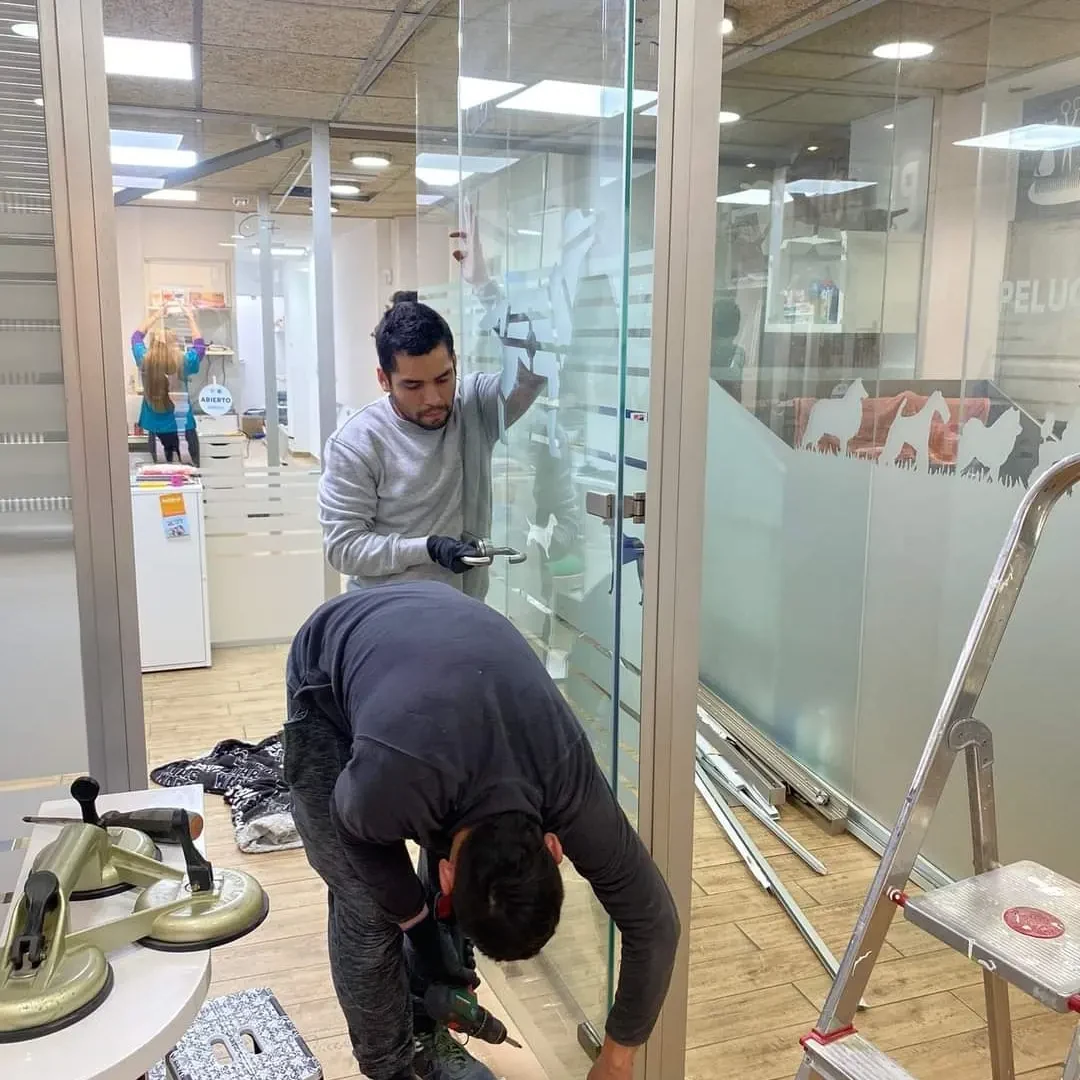 Compañeros desmontando una mampara de cristal