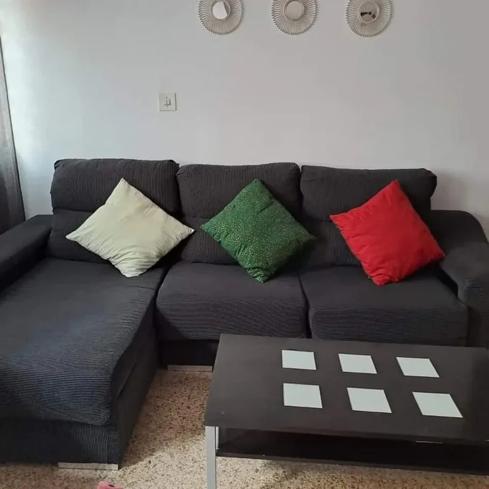 Sofá gris con cojines y mesa de centro en un salón