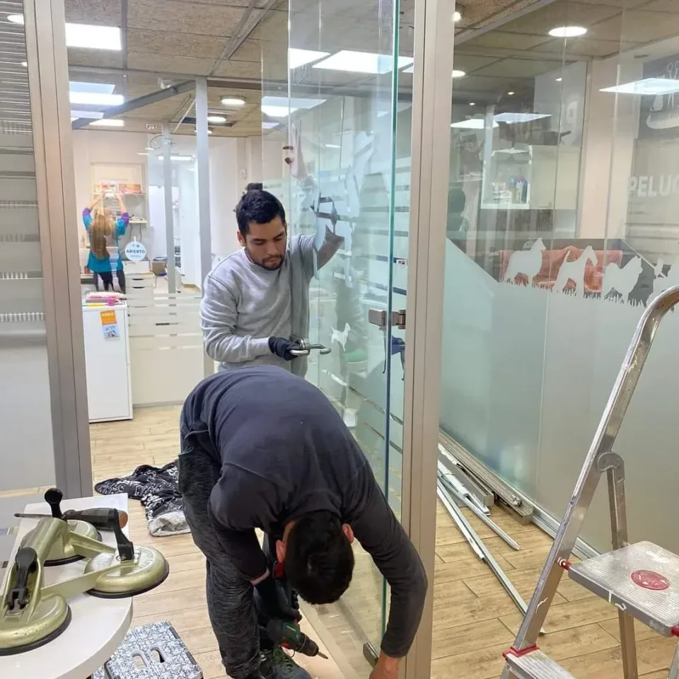 Dos miembros del equipo trabajando en una mampara de cristal